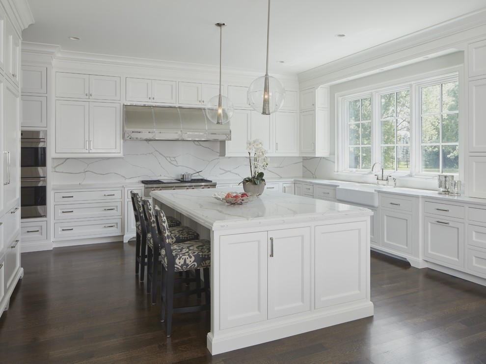 Inspiration for a transitional eat-in kitchen in Chicago with white cabinets, solid surface benchtops, white splashback, a farmhouse sink, shaker cabinets, stainless steel appliances, dark hardwood floors, with island and brown floor.