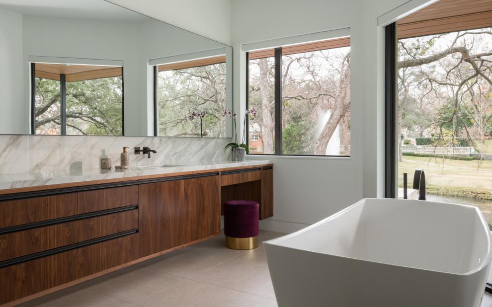 Photo of a contemporary master bathroom in Dallas with flat-panel cabinets, dark wood cabinets, a freestanding tub, multi-coloured tile, stone slab, white walls, an undermount sink, beige floor and multi-coloured benchtops.
