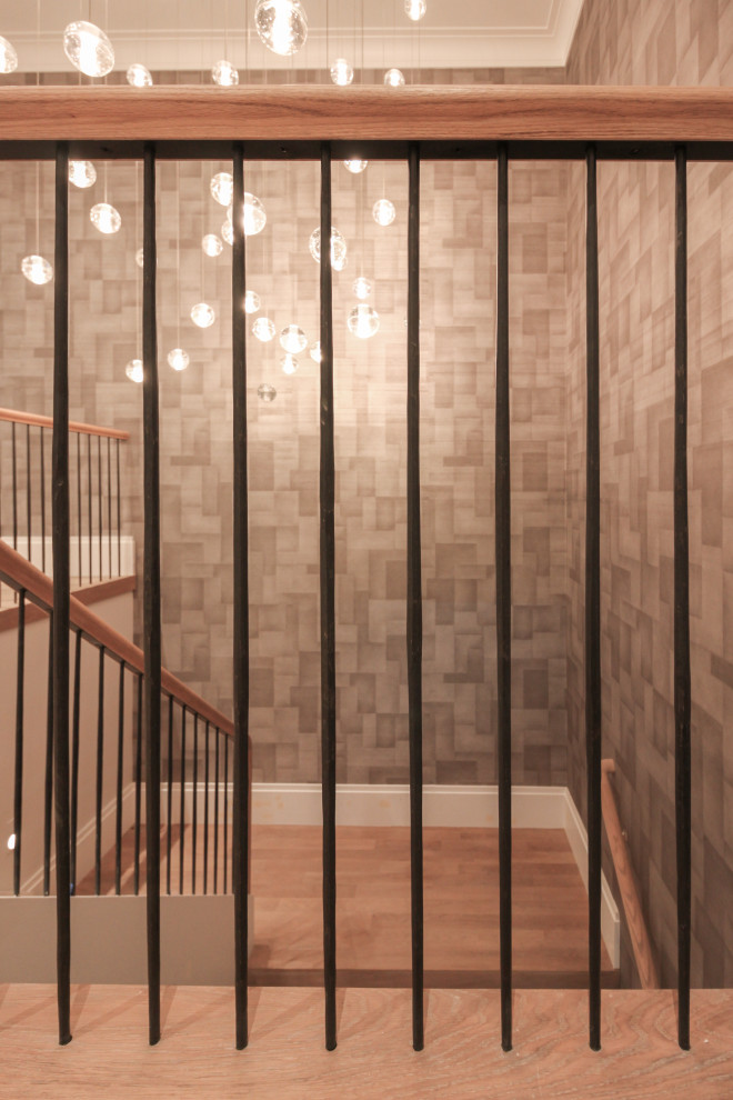 Large modern wood u-shaped staircase in DC Metro with wood risers, metal railing and wallpaper.