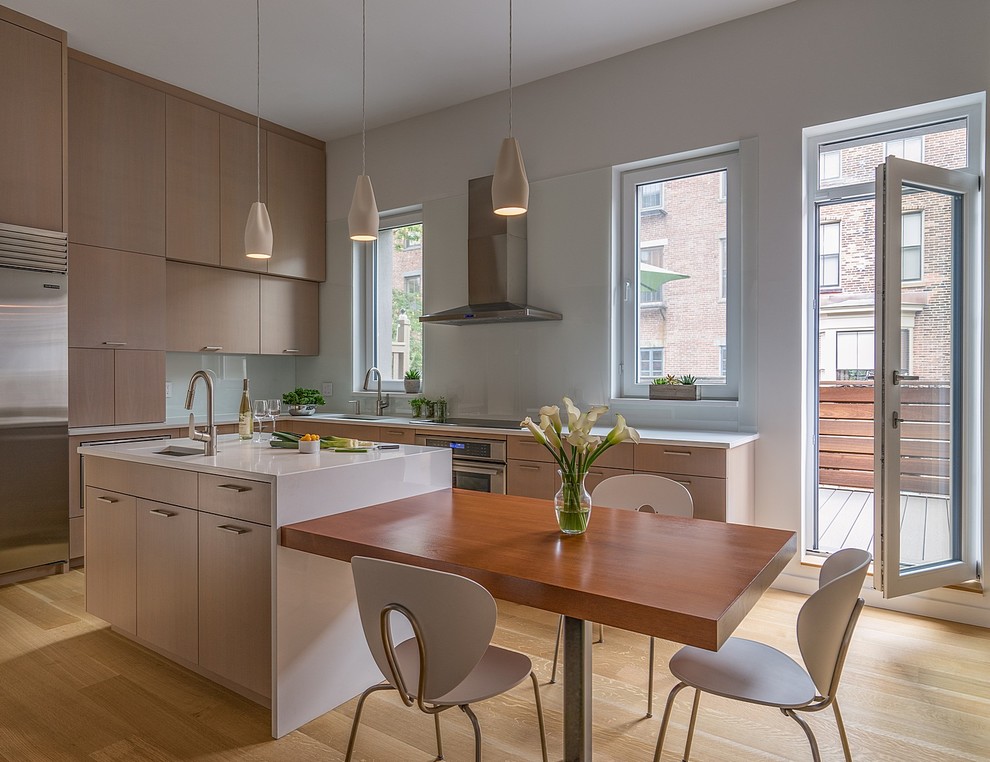 Inspiration for a mid-sized contemporary l-shaped medium tone wood floor and brown floor eat-in kitchen remodel in Boston with an undermount sink, flat-panel cabinets, light wood cabinets, quartz countertops, white backsplash, glass sheet backsplash, stainless steel appliances, an island and white countertops
