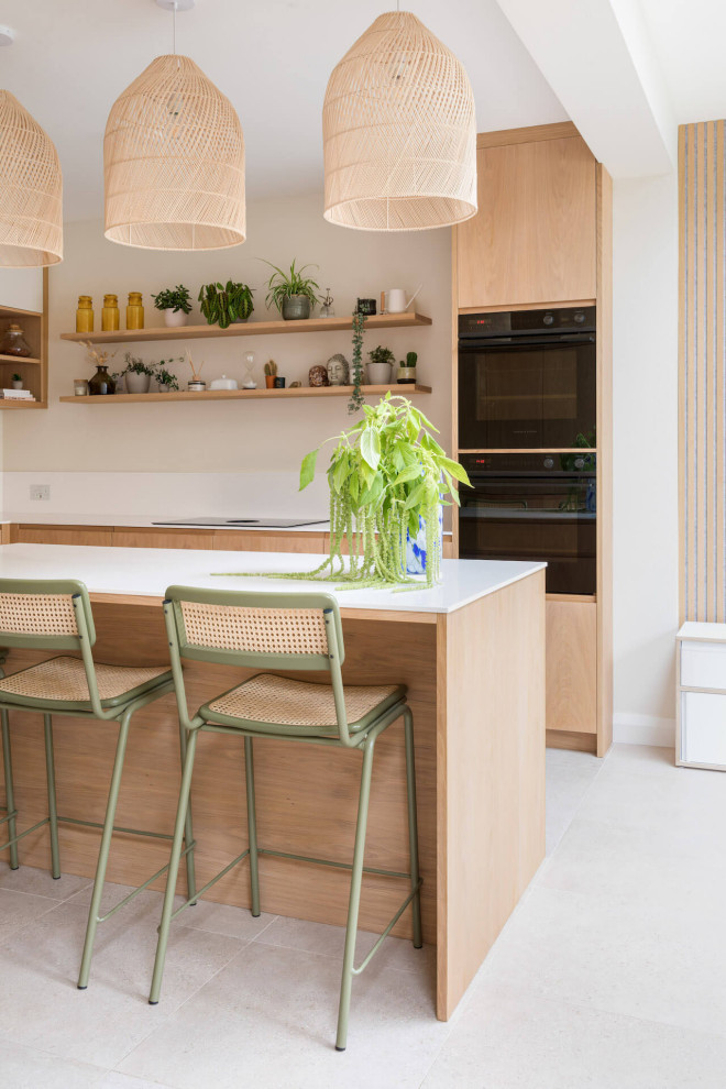 Example of a mid-sized danish kitchen design in London with medium tone wood cabinets, an island and white countertops