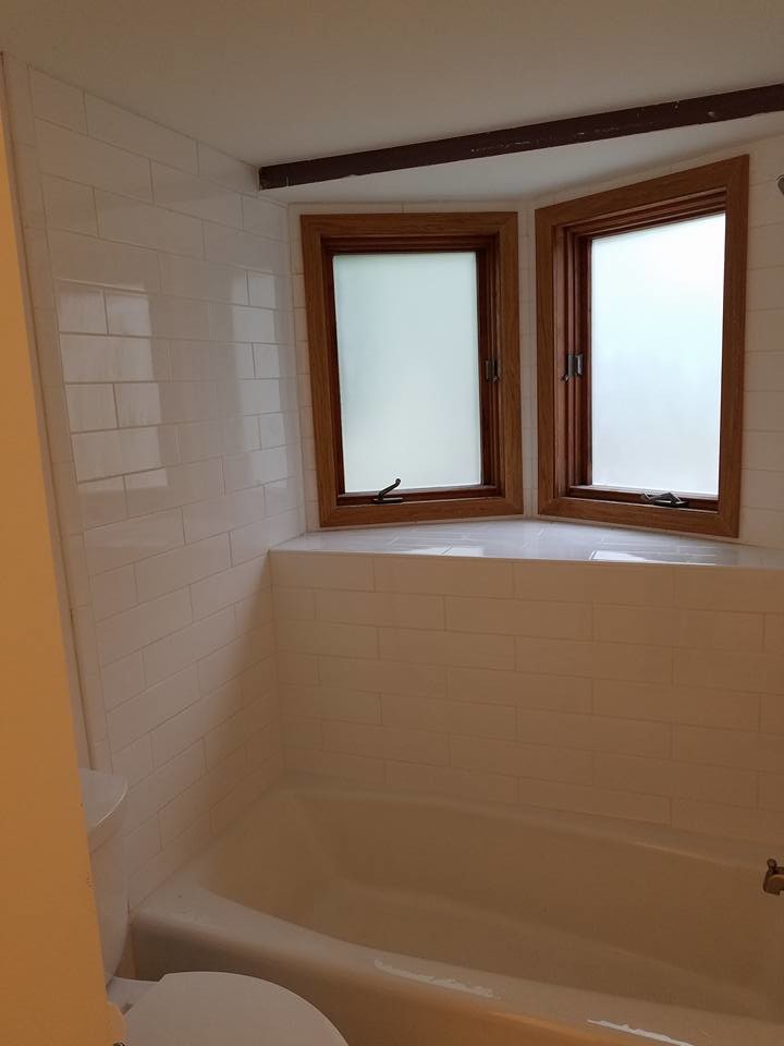 Example of a mid-sized transitional 3/4 white tile and subway tile laminate floor and beige floor alcove bathtub design with shaker cabinets, white cabinets, a two-piece toilet, beige walls, an undermount sink, solid surface countertops and white countertops