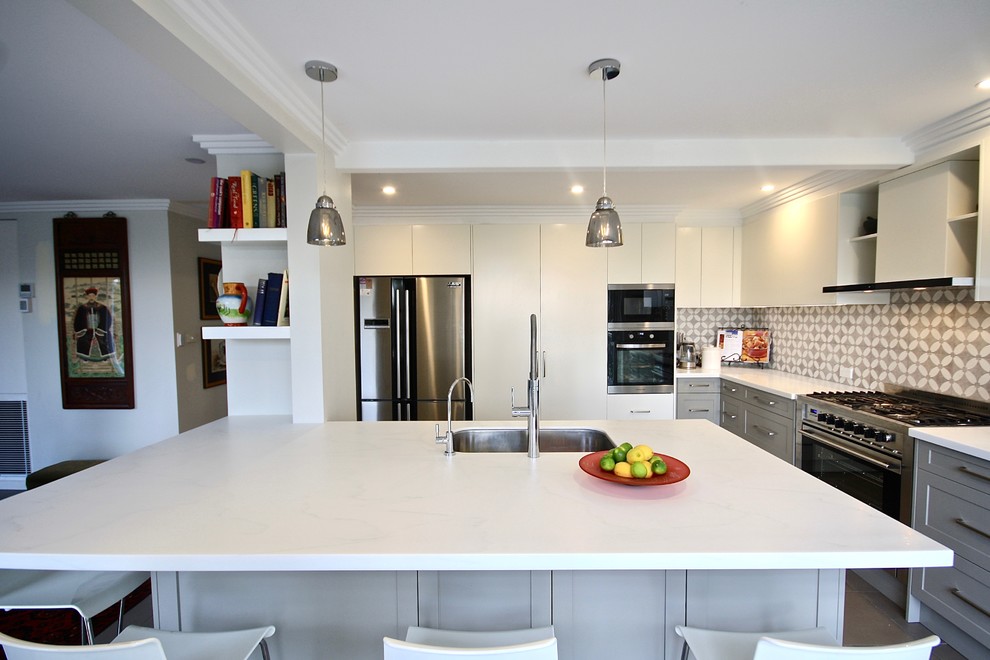 This is an example of a large modern u-shaped eat-in kitchen in Sydney with an undermount sink, shaker cabinets, grey cabinets, quartz benchtops, grey splashback, ceramic splashback, stainless steel appliances, porcelain floors, with island, beige floor and white benchtop.