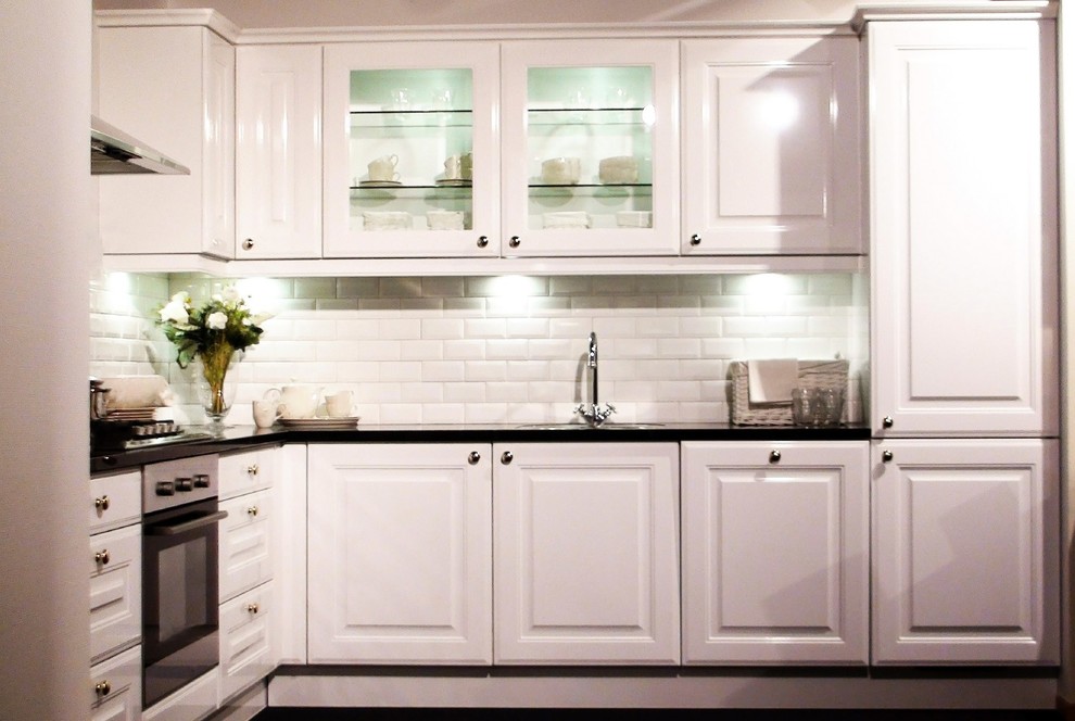 Kitchen - transitional l-shaped kitchen idea in Miami with raised-panel cabinets, white cabinets, quartzite countertops, white backsplash and subway tile backsplash