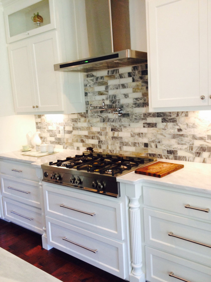 Example of a large transitional dark wood floor and brown floor kitchen design with shaker cabinets, white cabinets, marble countertops and marble backsplash