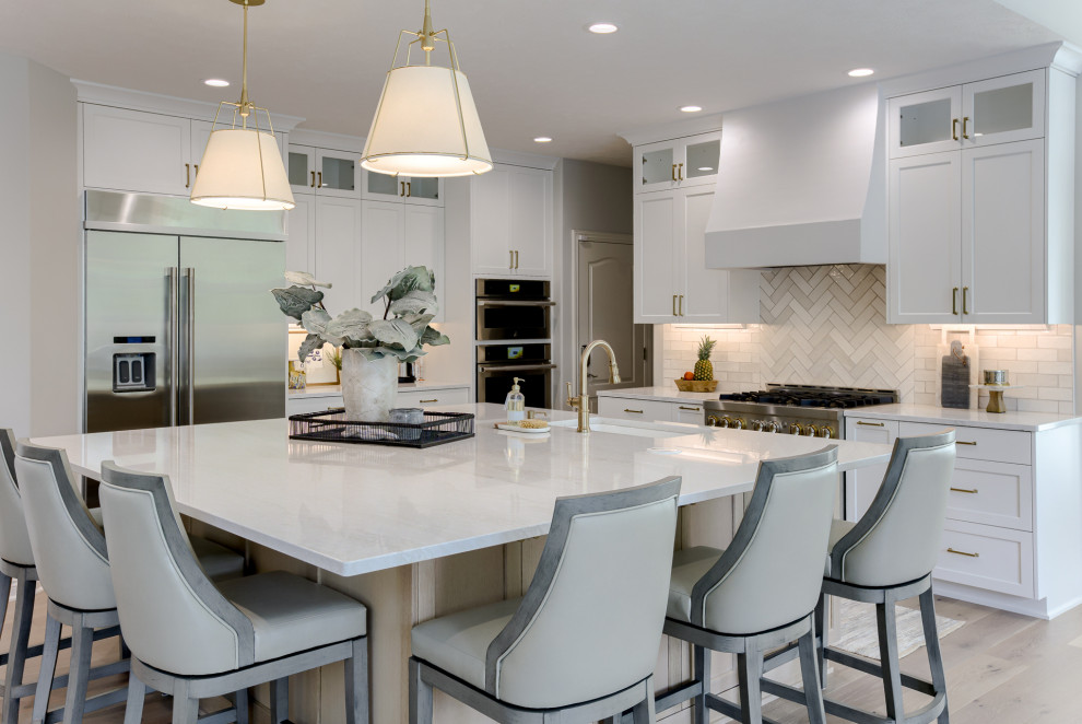 Open concept kitchen - transitional light wood floor and beige floor open concept kitchen idea with an undermount sink, white cabinets, quartzite countertops, multicolored backsplash, stainless steel appliances and an island