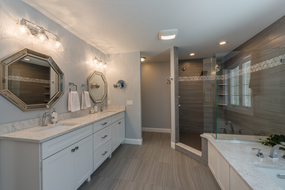 Photo of a mid-sized transitional 3/4 bathroom in New York with shaker cabinets, white cabinets, an alcove tub, a shower/bathtub combo, a two-piece toilet, beige tile, stone tile, grey walls, vinyl floors, an undermount sink, quartzite benchtops, beige floor and a shower curtain.
