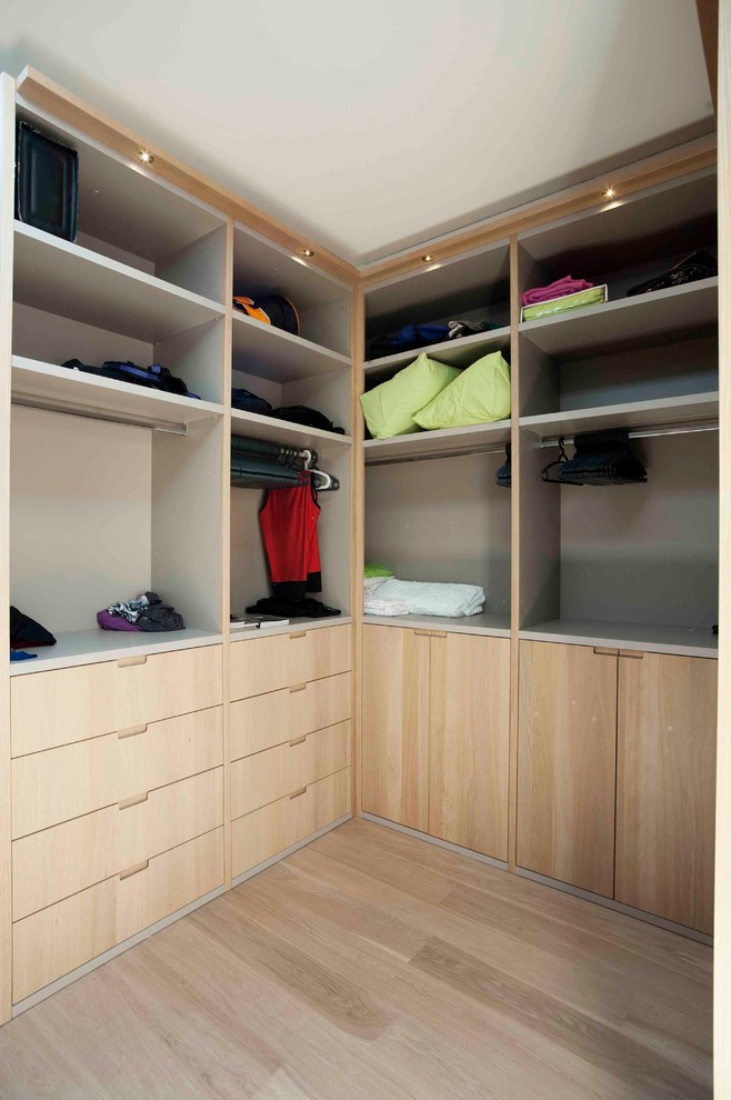 Photo of a large contemporary gender-neutral walk-in wardrobe in New York with flat-panel cabinets, medium wood cabinets and light hardwood floors.