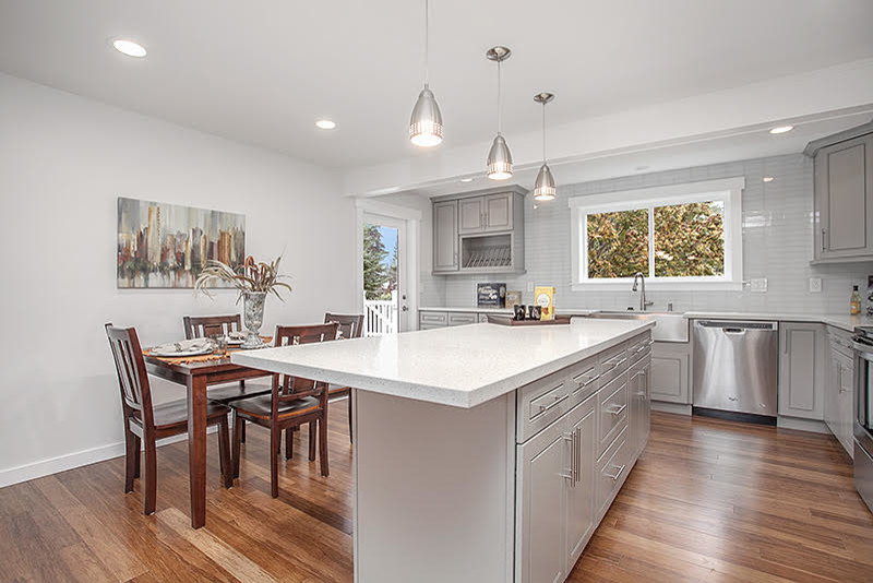 Example of a transitional medium tone wood floor eat-in kitchen design in Seattle with raised-panel cabinets, gray cabinets, quartzite countertops, white backsplash, glass tile backsplash, stainless steel appliances and an island