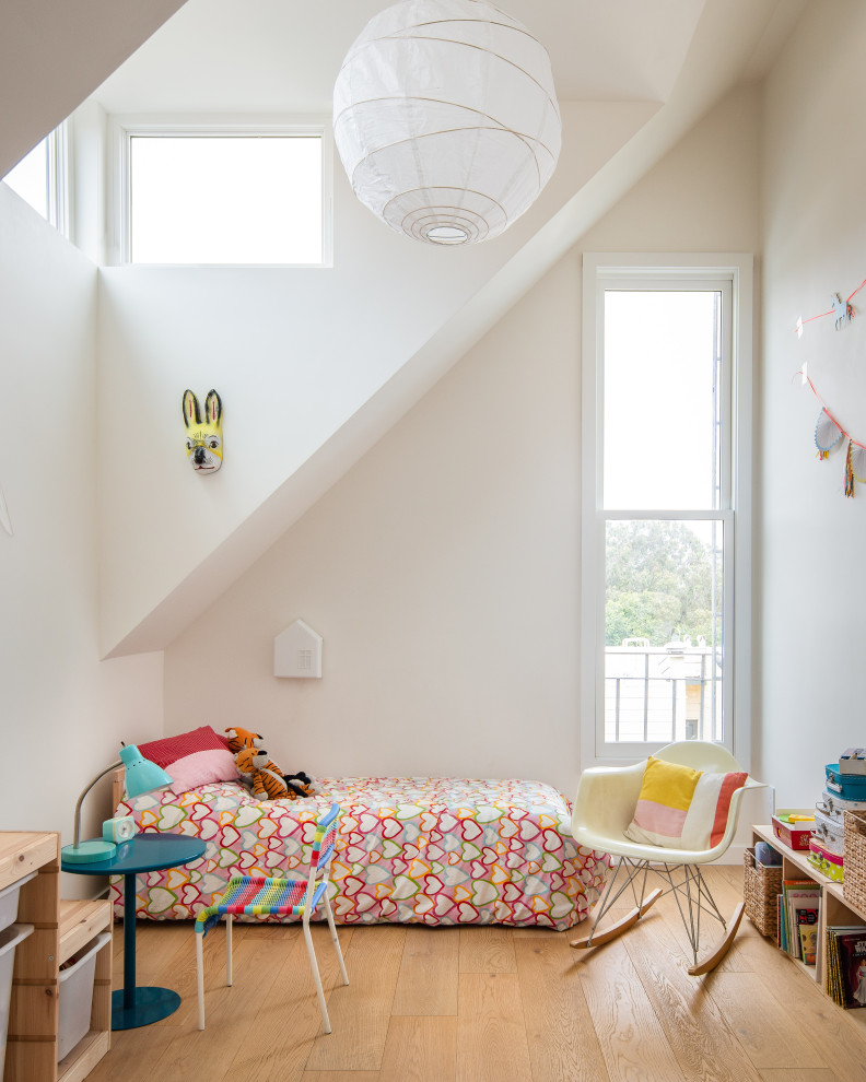 This is an example of a scandinavian kids' room in San Francisco with white walls, medium hardwood floors and brown floor.