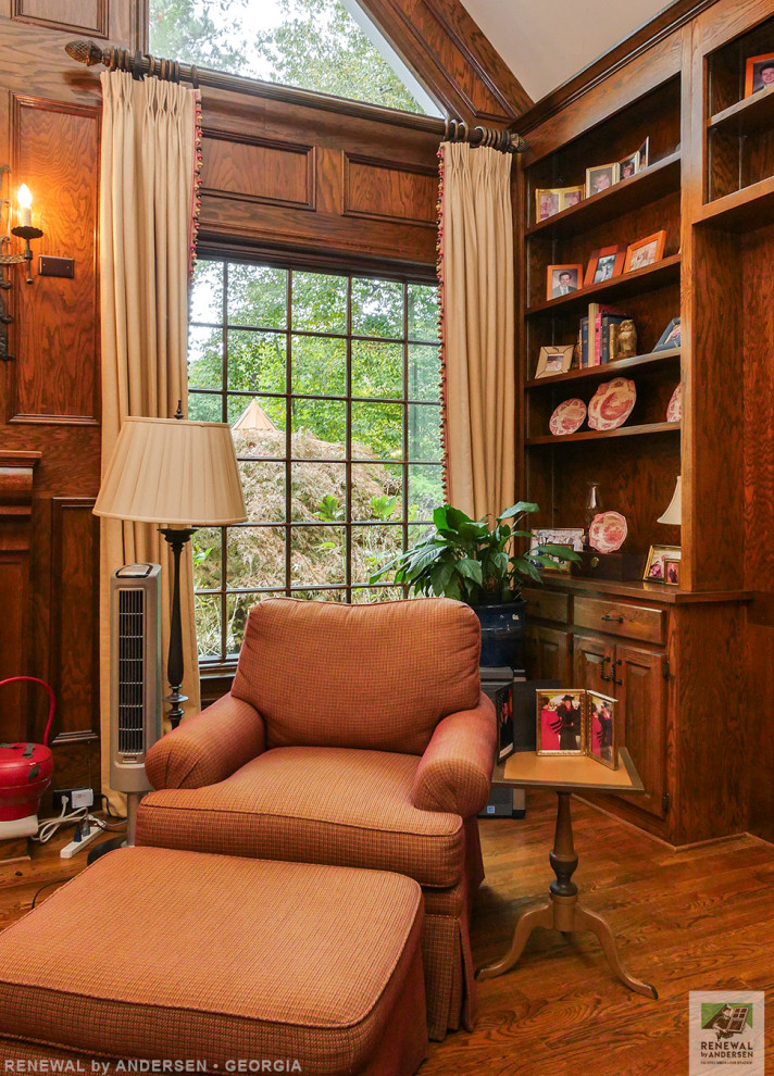 Große, Abgetrennte Bibliothek mit braunem Holzboden, Kamin, Kaminumrandung aus Holz, freistehendem TV, gewölbter Decke und Wandpaneelen in Atlanta