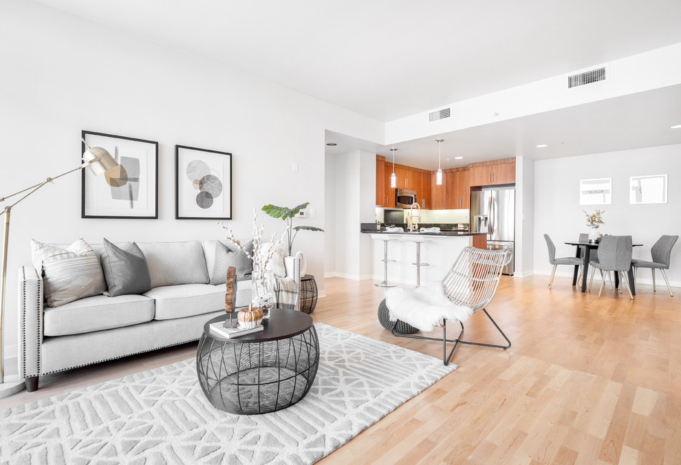 This is an example of a small modern open concept living room in San Francisco with white walls, light hardwood floors, no fireplace and beige floor.