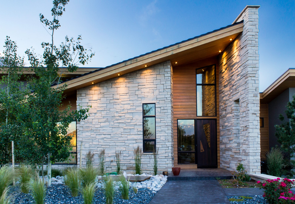 This is an example of a large contemporary two-storey grey exterior in Denver with stone veneer and a shed roof.