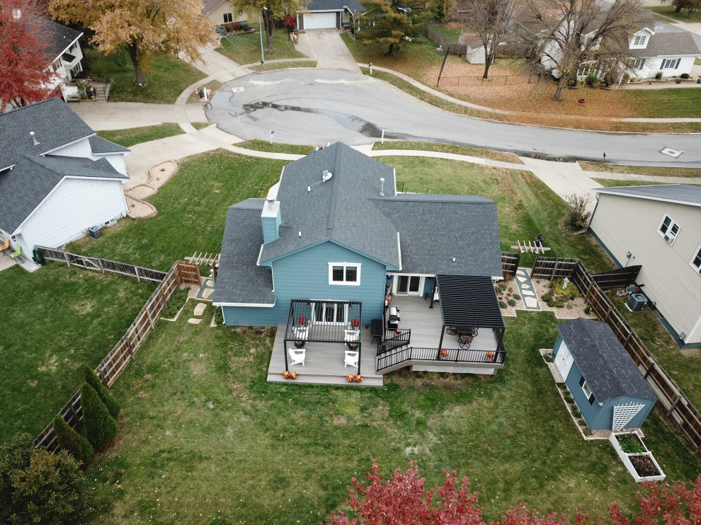 Example of a large backyard ground level metal railing deck design with a pergola