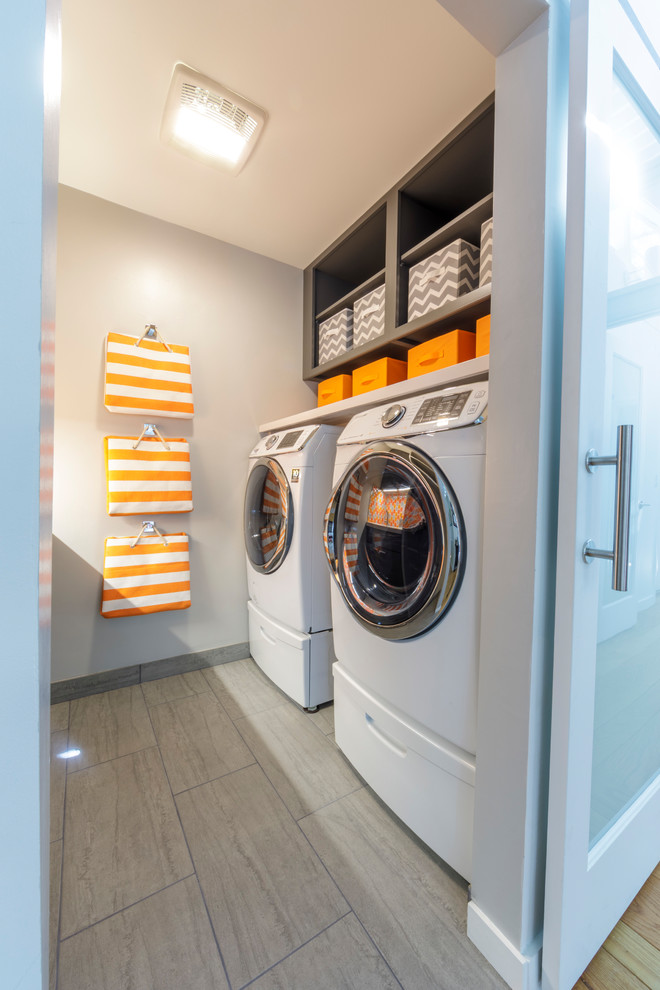 Small midcentury galley laundry room in San Francisco with an undermount sink, flat-panel cabinets, grey cabinets, quartz benchtops, grey walls, porcelain floors, a side-by-side washer and dryer, grey floor and white benchtop.