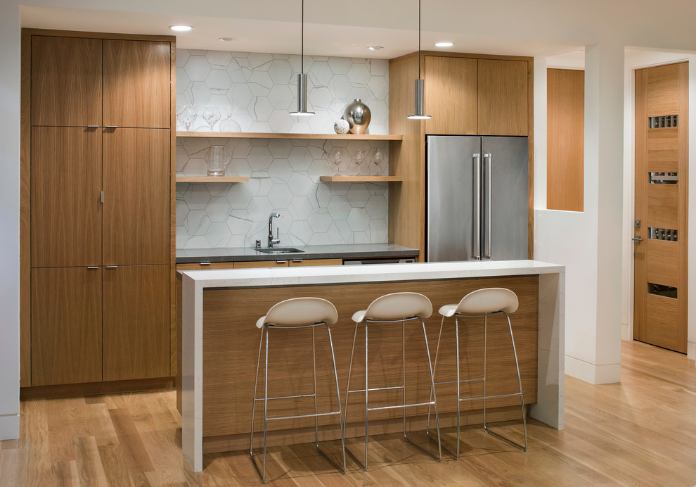 Inspiration for a mid-sized contemporary galley open plan kitchen in San Francisco with an undermount sink, flat-panel cabinets, medium wood cabinets, quartz benchtops, white splashback, porcelain splashback, stainless steel appliances, light hardwood floors, with island and beige floor.