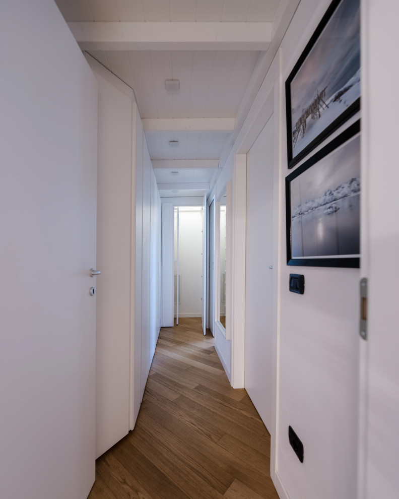На фото: маленький коридор в скандинавском стиле с белыми стенами, полом из ламината, коричневым полом и деревянным потолком для на участке и в саду