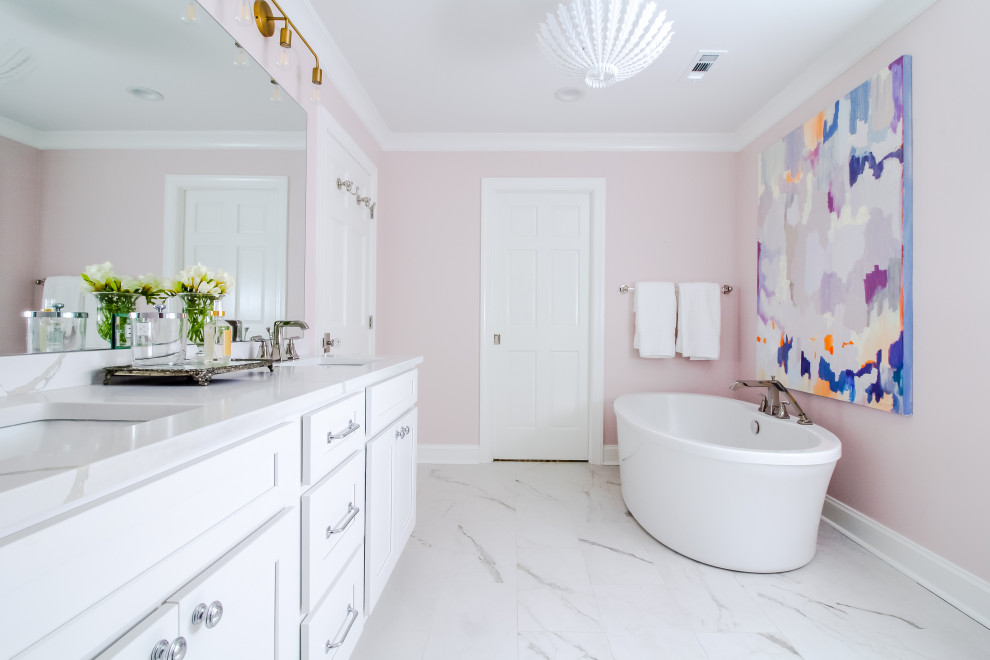 На фото: главная ванная комната среднего размера в стиле неоклассика (современная классика) с фасадами в стиле шейкер, белыми фасадами, отдельно стоящей ванной, угловым душем, белой плиткой, керамической плиткой, розовыми стенами, врезной раковиной, столешницей из искусственного кварца, душем с распашными дверями, белой столешницей, тумбой под две раковины и напольной тумбой с