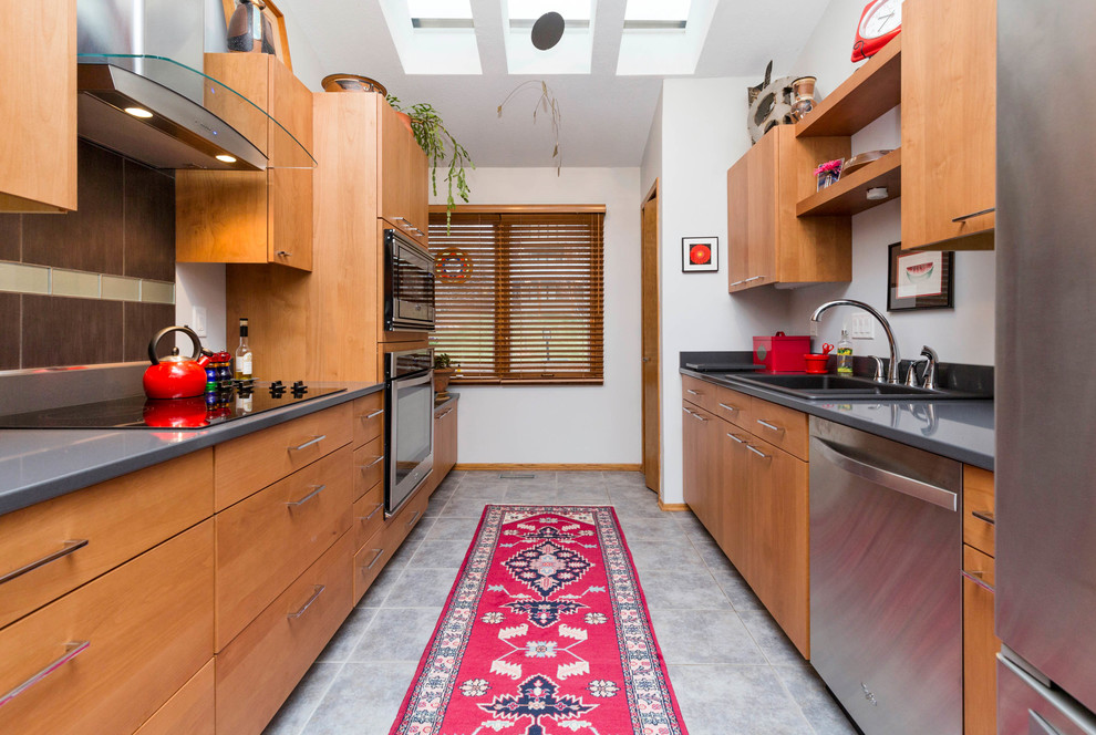 Large modern galley eat-in kitchen in Other with a drop-in sink, flat-panel cabinets, light wood cabinets, soapstone benchtops, grey splashback, stone tile splashback, stainless steel appliances, porcelain floors, a peninsula and grey floor.