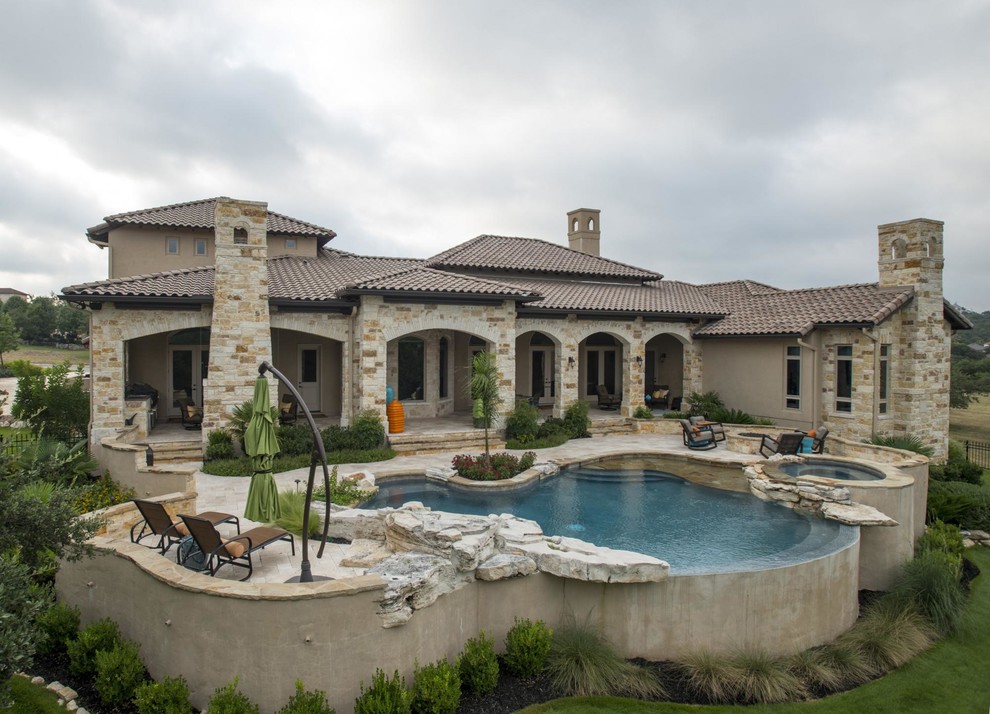 Traditional backyard custom-shaped aboveground pool in Austin with a hot tub and natural stone pavers.