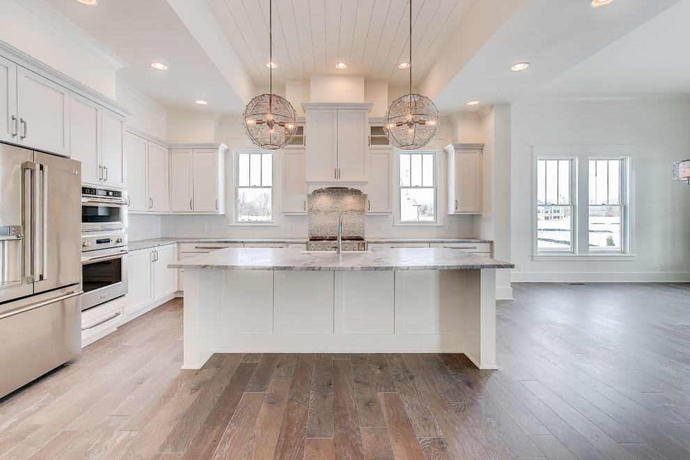 Inspiration for a large arts and crafts l-shaped eat-in kitchen in Indianapolis with a farmhouse sink, shaker cabinets, white cabinets, quartzite benchtops, blue splashback, ceramic splashback, stainless steel appliances, light hardwood floors, with island and brown floor.