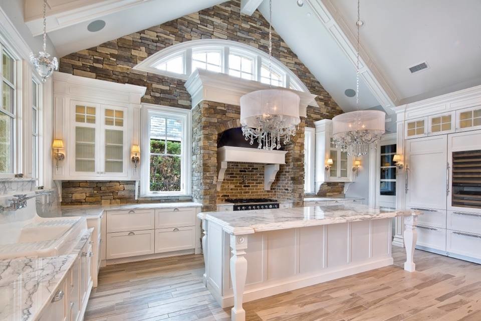 Large traditional u-shaped open plan kitchen in Houston with a drop-in sink, white cabinets, marble benchtops, brown splashback, stone slab splashback, stainless steel appliances, light hardwood floors and with island.