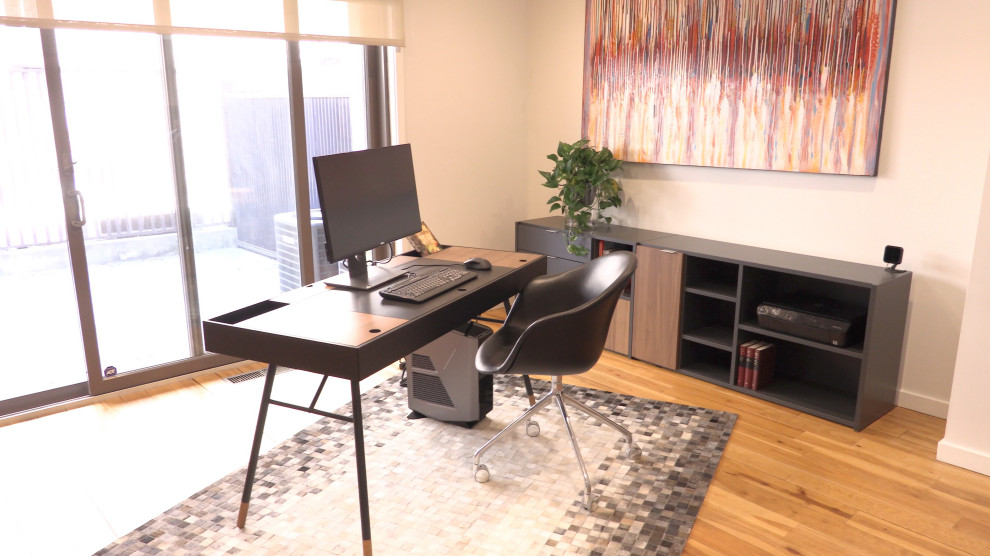 This is an example of a mid-sized scandinavian home office in Philadelphia with white walls, medium hardwood floors, a freestanding desk and brown floor.