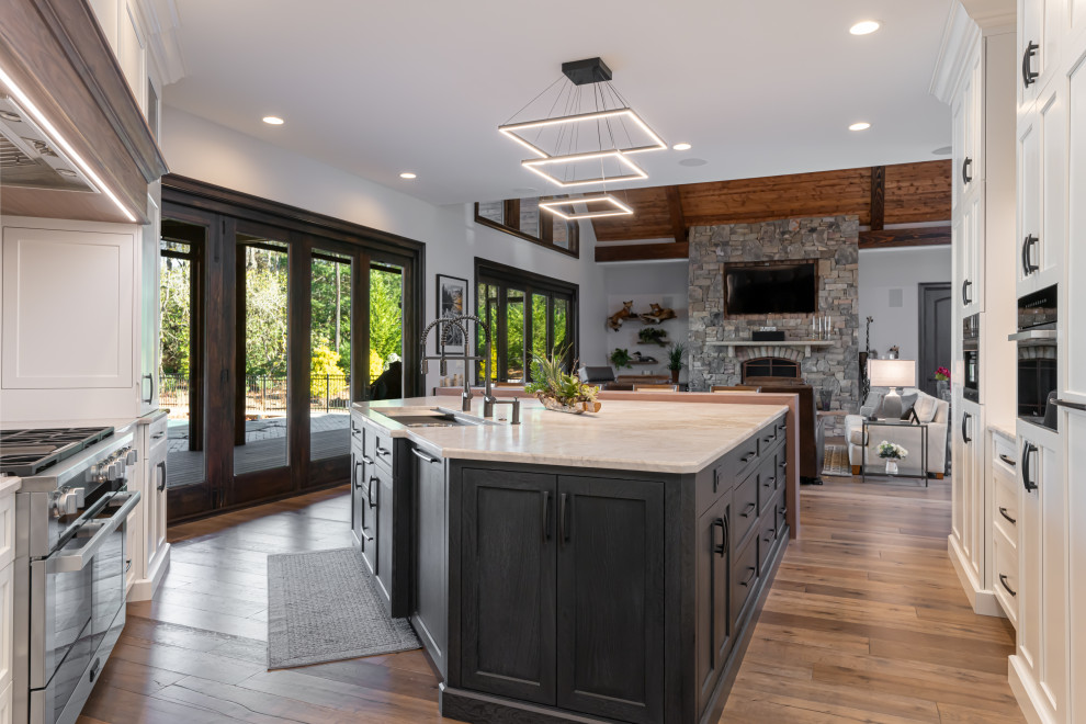 Open concept kitchen - large transitional medium tone wood floor and brown floor open concept kitchen idea with a double-bowl sink, flat-panel cabinets, white cabinets, quartzite countertops, beige backsplash, stainless steel appliances, an island and beige countertops