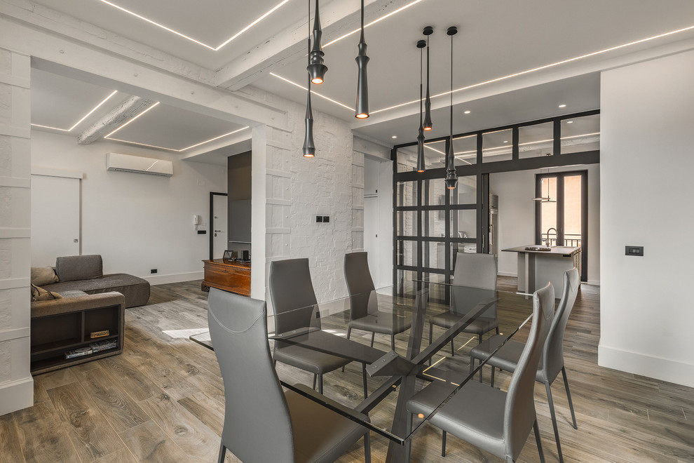 Design ideas for an industrial open plan dining in Bologna with white walls, medium hardwood floors and brown floor.