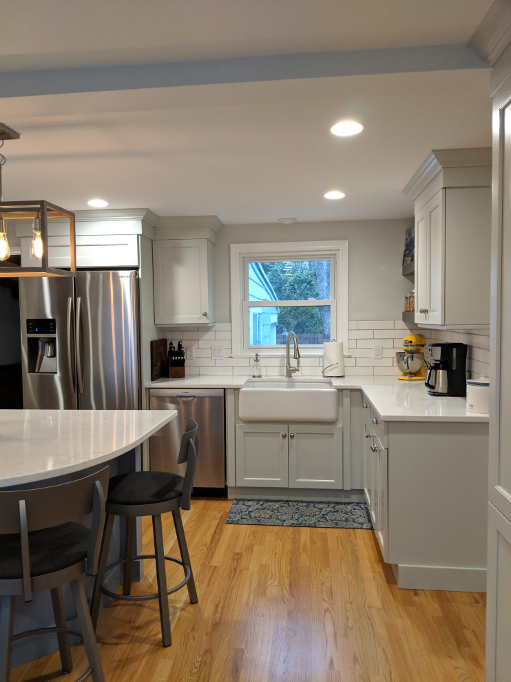 Small transitional u-shaped medium tone wood floor open concept kitchen photo in Boston with a farmhouse sink, shaker cabinets, blue cabinets, quartzite countertops, gray backsplash, mosaic tile backsplash, stainless steel appliances, an island and white countertops
