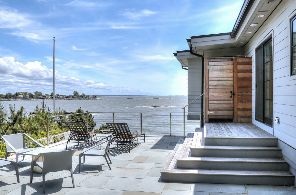 Foto på en mellanstor skandinavisk uteplats på baksidan av huset, med utedusch och naturstensplattor