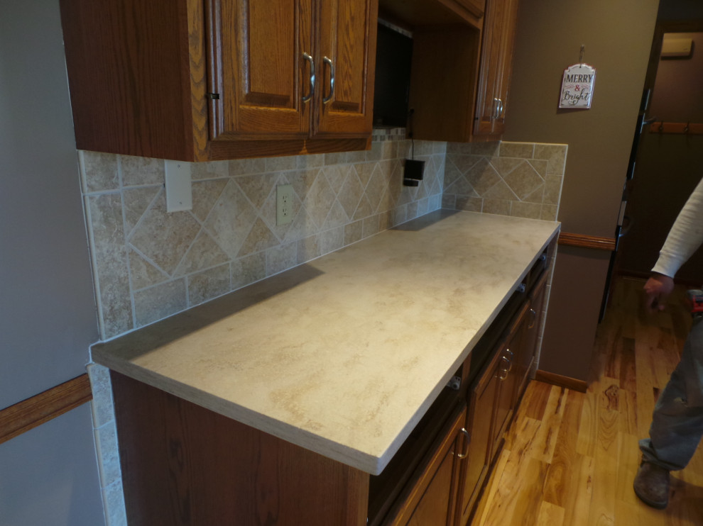 Inspiration for a large contemporary l-shaped light wood floor and brown floor enclosed kitchen remodel with an undermount sink, raised-panel cabinets, medium tone wood cabinets, solid surface countertops, beige backsplash, ceramic backsplash, stainless steel appliances, an island and beige countertops