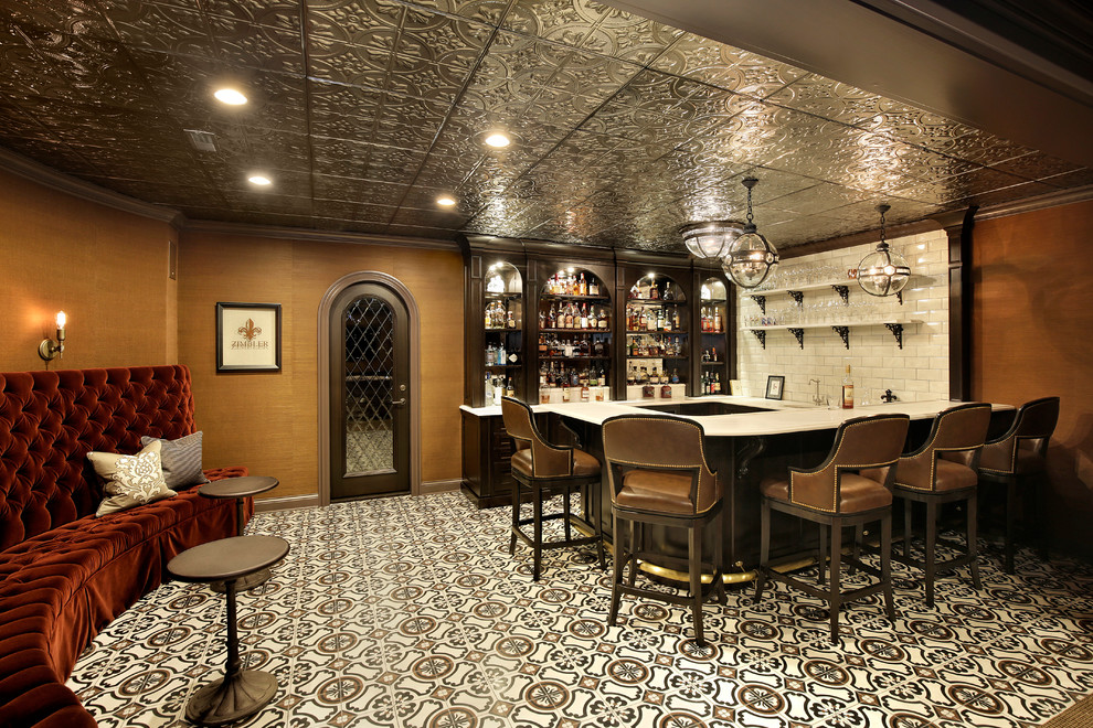 Photo of a large traditional u-shaped seated home bar in Chicago with a drop-in sink, recessed-panel cabinets, dark wood cabinets, granite benchtops, white splashback, mirror splashback, ceramic floors, multi-coloured floor and white benchtop.