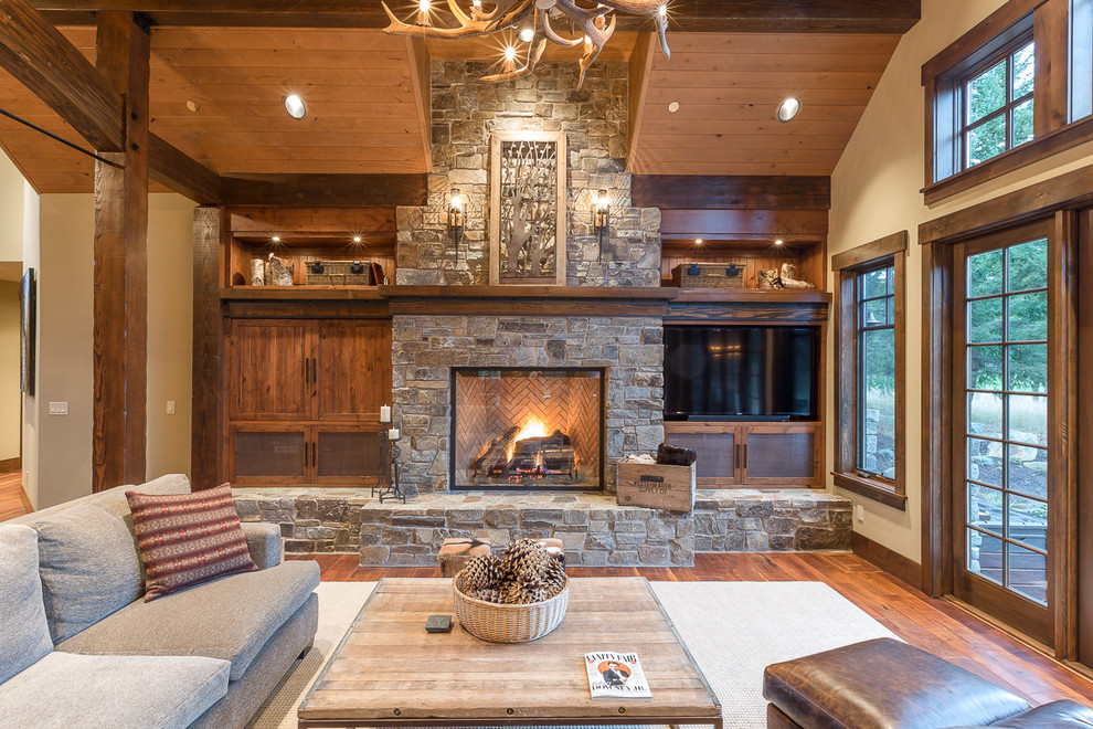 Inspiration for a country family room in Seattle with beige walls, medium hardwood floors, a standard fireplace, a stone fireplace surround and a built-in media wall.