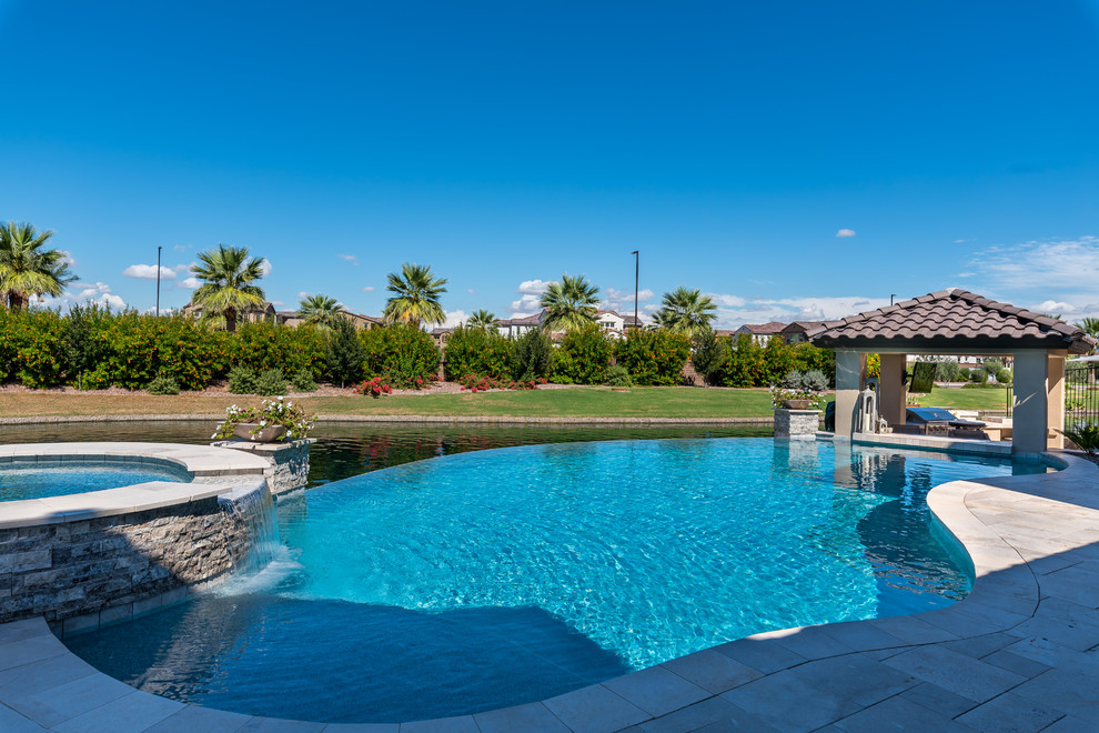 This is an example of a mid-sized contemporary backyard kidney-shaped infinity pool in Phoenix with a hot tub and tile.