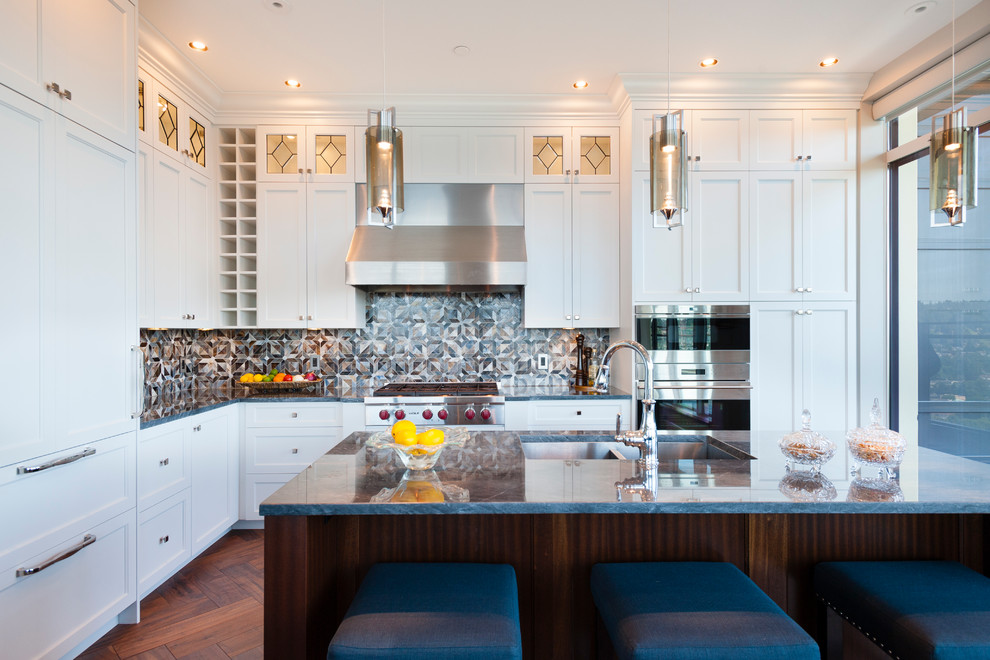 This is an example of a mid-sized transitional l-shaped open plan kitchen in Vancouver with an undermount sink, shaker cabinets, white cabinets, marble benchtops, multi-coloured splashback, glass tile splashback, stainless steel appliances, medium hardwood floors and with island.