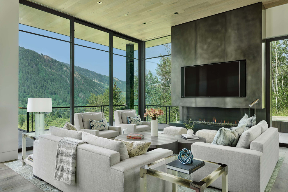 This is an example of a contemporary living room in Denver with a ribbon fireplace, a metal fireplace surround, a wall mounted tv, grey floors and a wood ceiling.