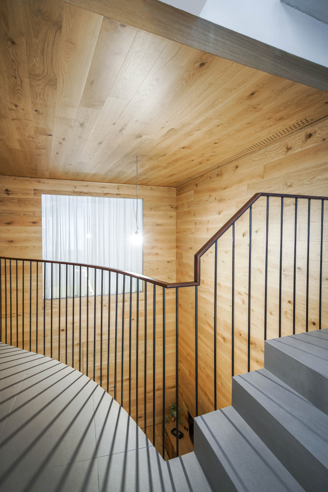 На фото: лестница в скандинавском стиле с ступенями из плитки, подступенками из плитки, металлическими перилами и деревянными стенами с