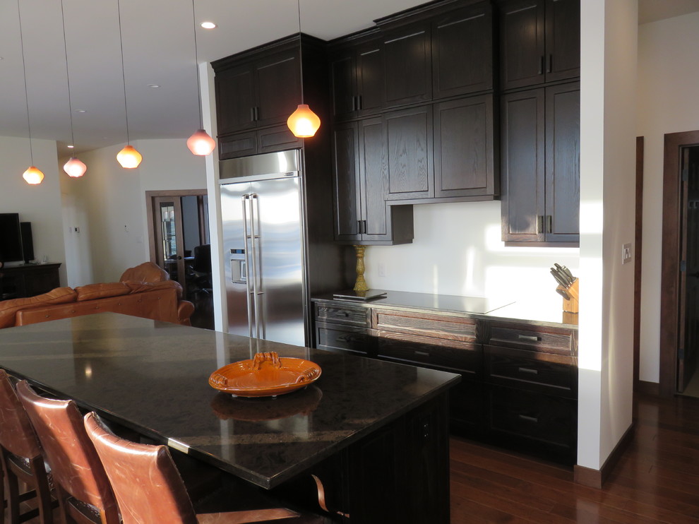 Large transitional l-shaped dark wood floor open concept kitchen photo with recessed-panel cabinets, dark wood cabinets, quartz countertops, stainless steel appliances, an island and an undermount sink