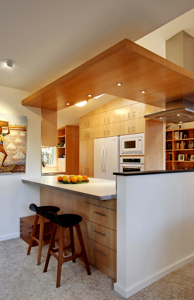 This is an example of a contemporary separate kitchen in Seattle with flat-panel cabinets, light wood cabinets and white appliances.