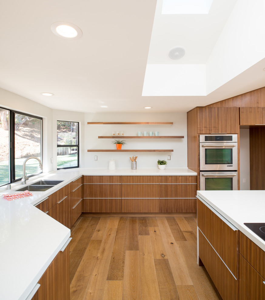 Inspiration for a large contemporary u-shaped open plan kitchen in San Diego with an undermount sink, flat-panel cabinets, dark wood cabinets, quartz benchtops, white splashback, stainless steel appliances, medium hardwood floors and with island.