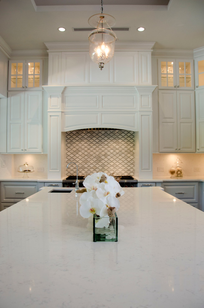 Large transitional u-shaped enclosed kitchen photo in Miami with a farmhouse sink, raised-panel cabinets, white cabinets, quartz countertops, gray backsplash, porcelain backsplash, paneled appliances and an island