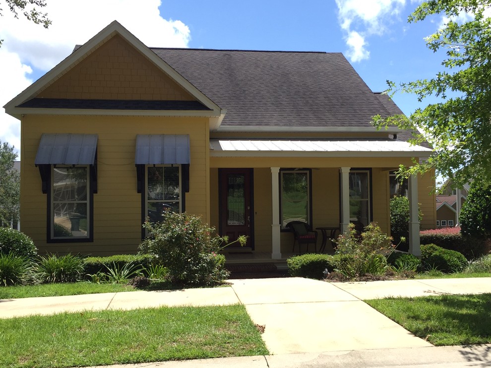 Photo of a mid-sized transitional one-storey yellow house exterior in Miami with vinyl siding, a gable roof and a shingle roof.