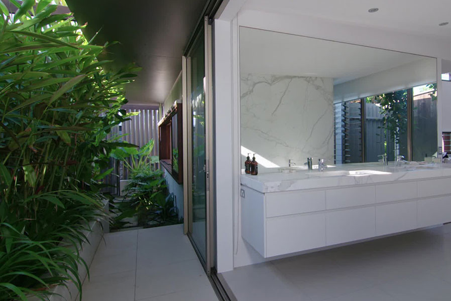 This is an example of a beach style bathroom in Sydney with white tile, white walls and marble benchtops.
