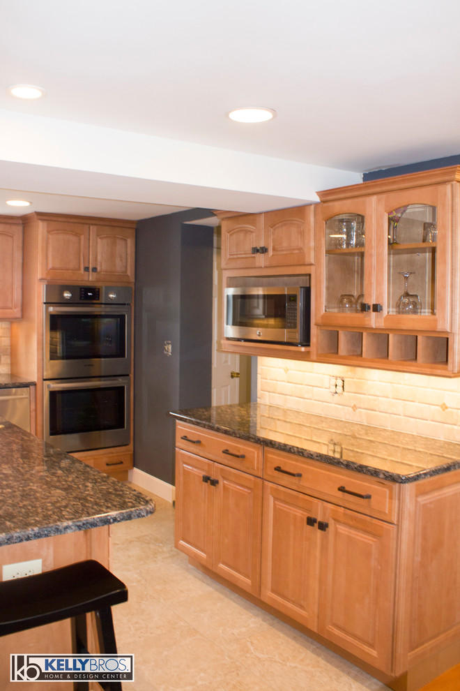 Eat-in kitchen - large transitional l-shaped ceramic tile eat-in kitchen idea in Cincinnati with an undermount sink, raised-panel cabinets, light wood cabinets, granite countertops, beige backsplash, stone tile backsplash, stainless steel appliances and an island