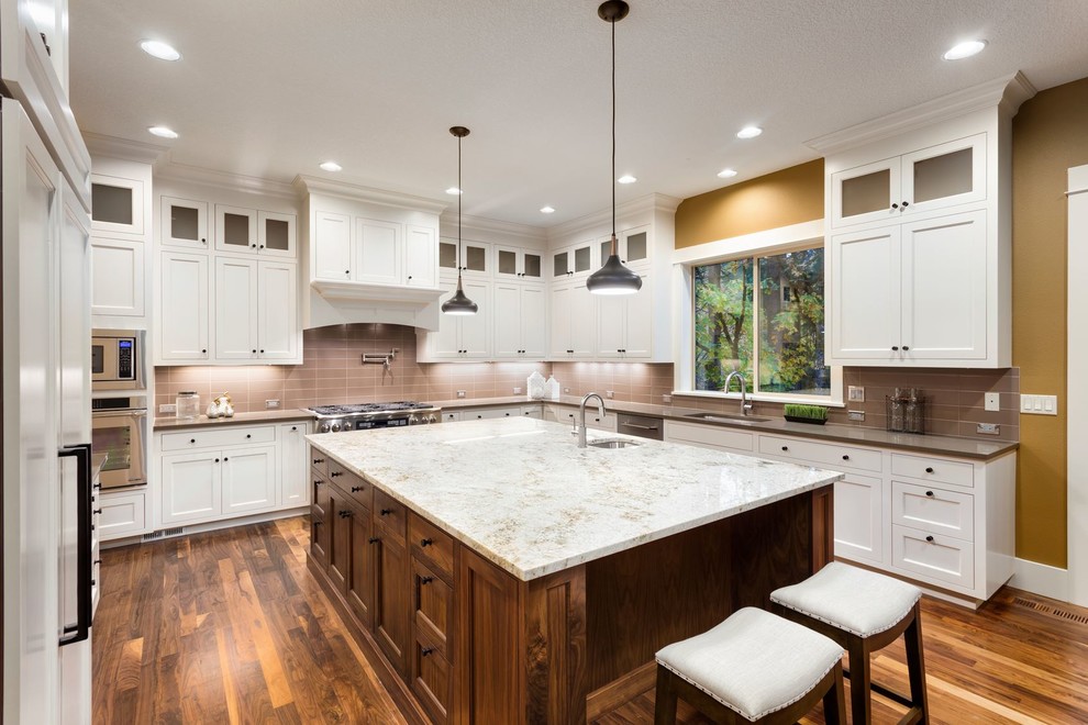 Transitional u-shaped medium tone wood floor kitchen photo in Miami with a single-bowl sink, shaker cabinets, white cabinets, quartzite countertops, brown backsplash, glass tile backsplash, stainless steel appliances and an island