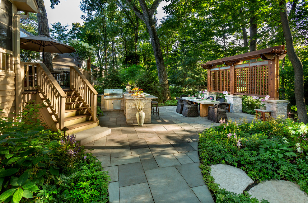 This is an example of a traditional backyard shaded garden for summer in Chicago with a garden path and natural stone pavers.