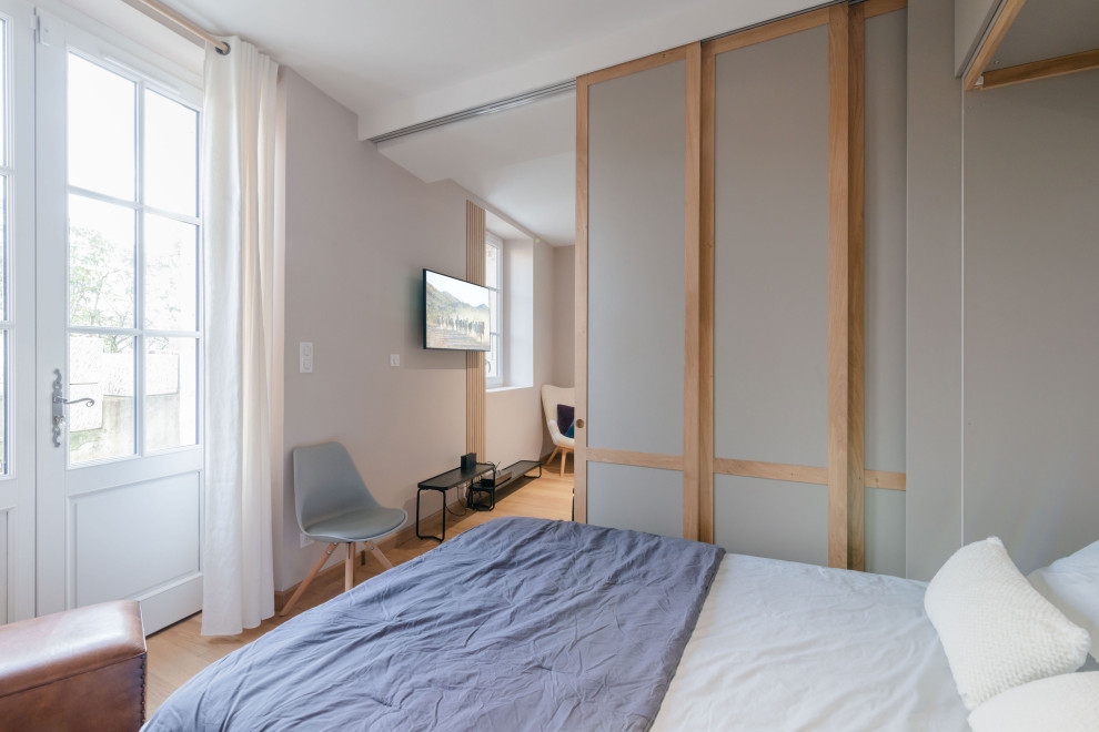 Cette image montre une chambre d'amis beige et blanche minimaliste de taille moyenne avec un mur beige, parquet clair et dressing.