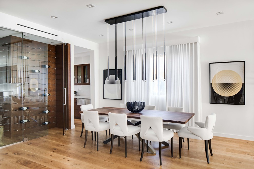 Contemporary dining room in Los Angeles with white walls, medium hardwood floors and brown floor.