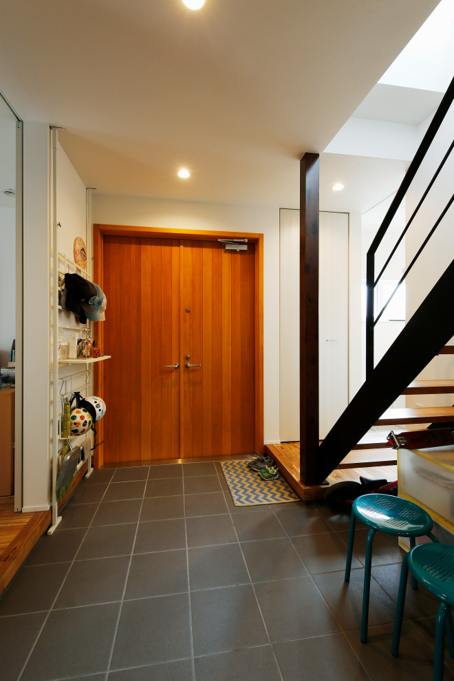 This is an example of a mid-sized industrial mudroom in Tokyo with white walls, porcelain floors, a double front door, a medium wood front door and grey floor.